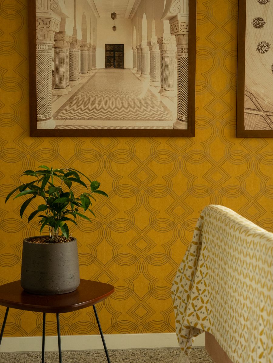 A yellow patterned wallpaper accent wall with framed art